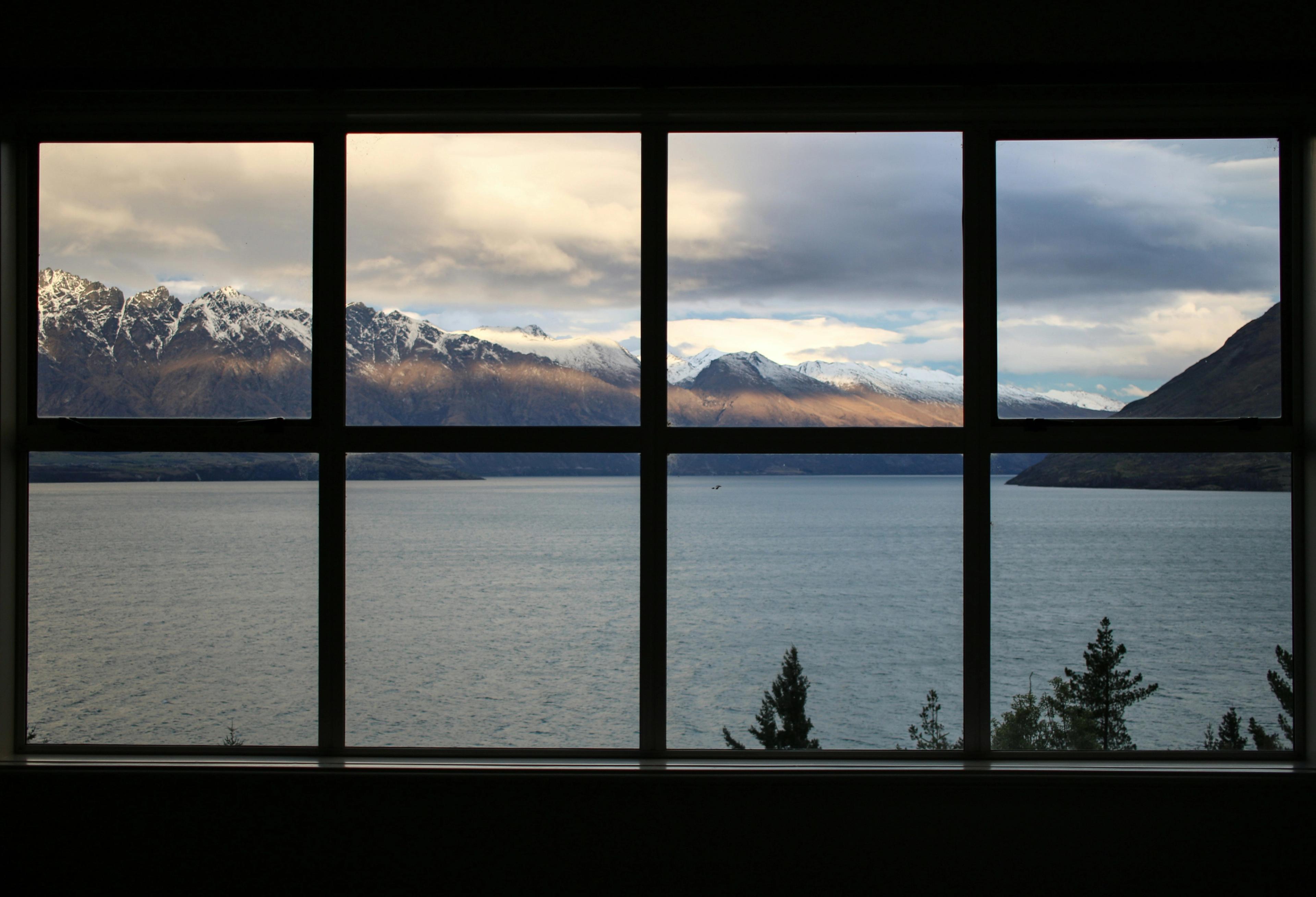 a window with a view of a lake and mountains