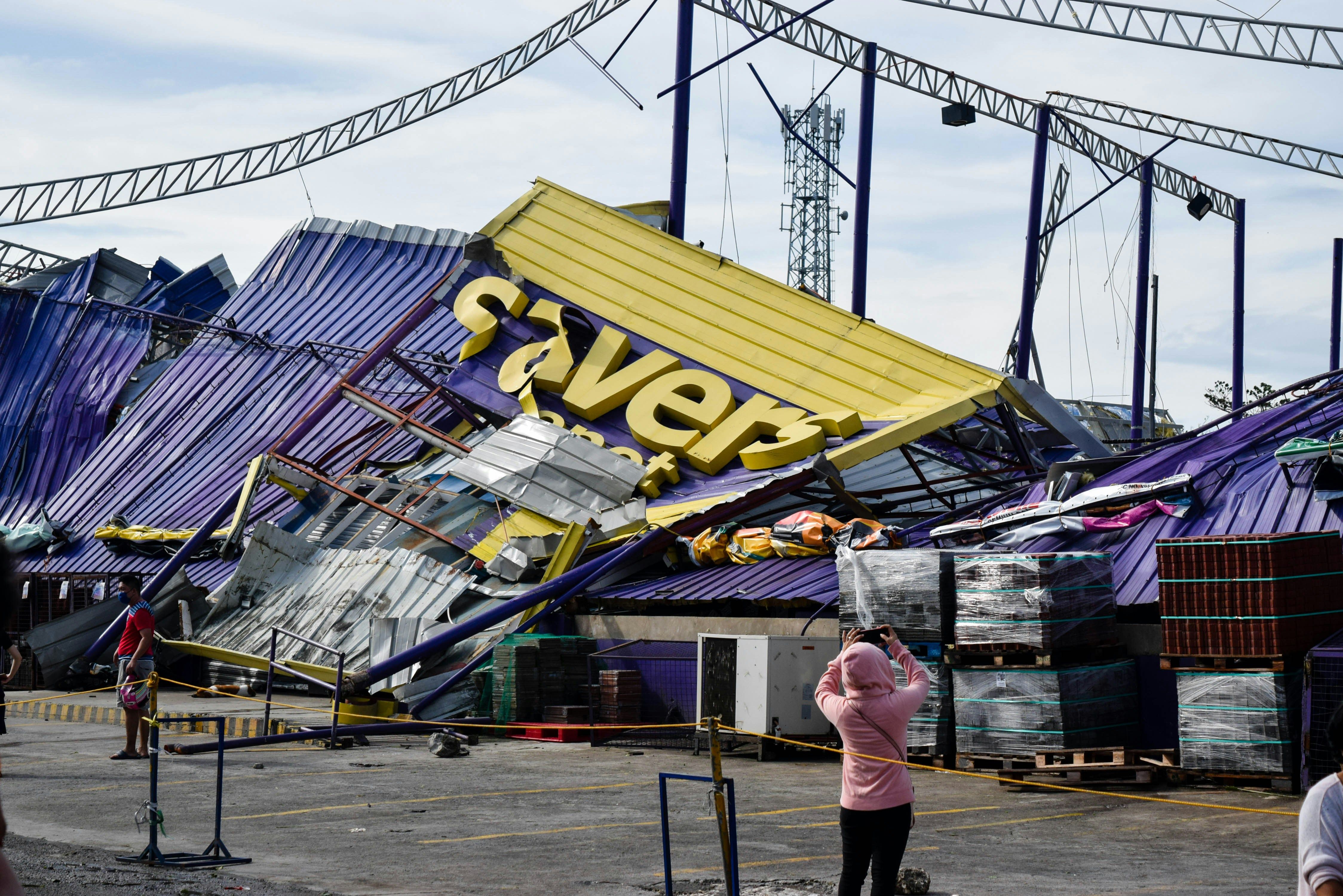 a woman is taking a picture of a building that has fallen down .