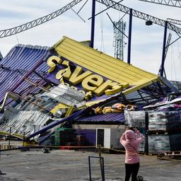 a woman is taking a picture of a building that has fallen down .