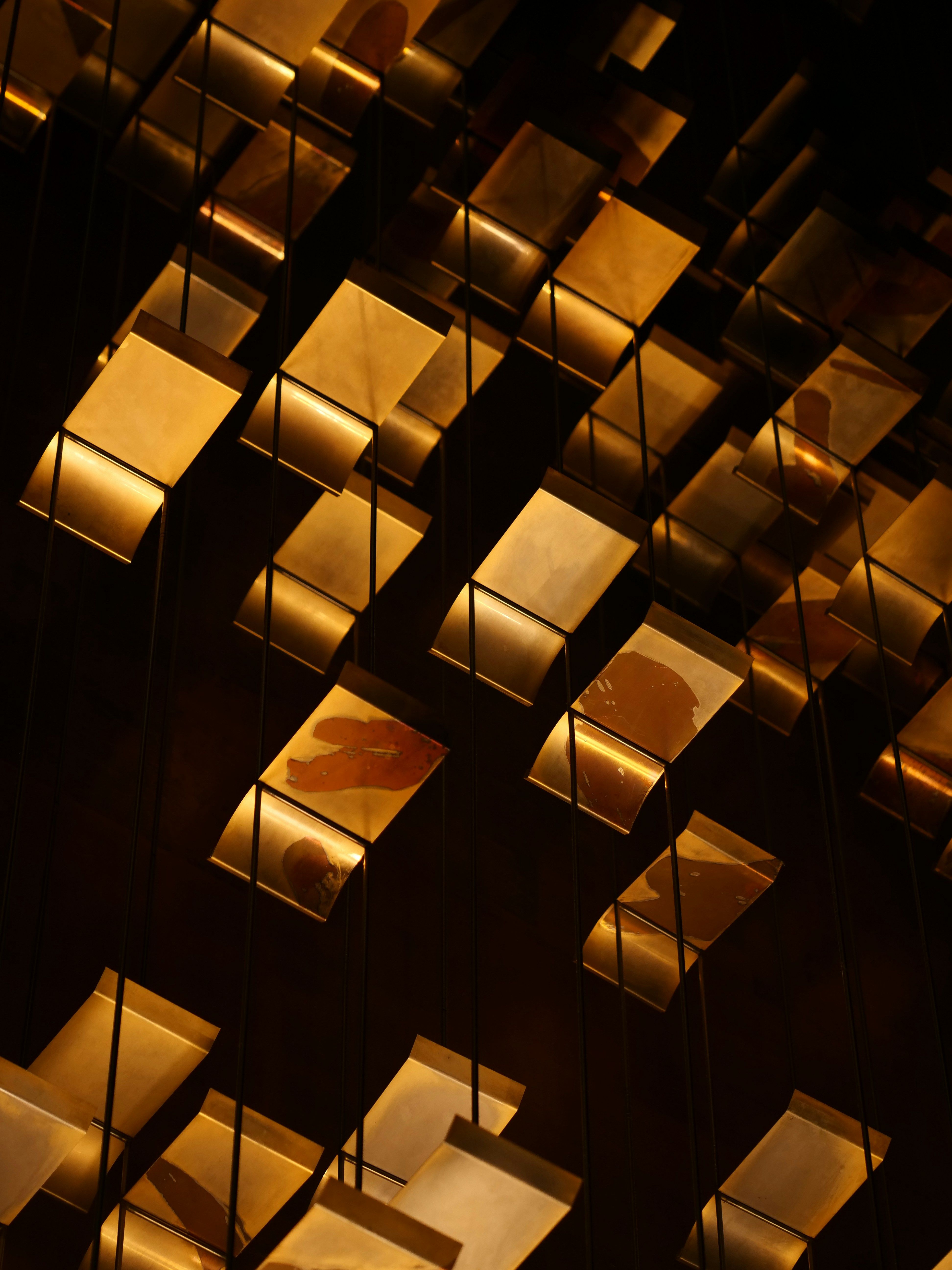 a bunch of gold squares are hanging from the ceiling