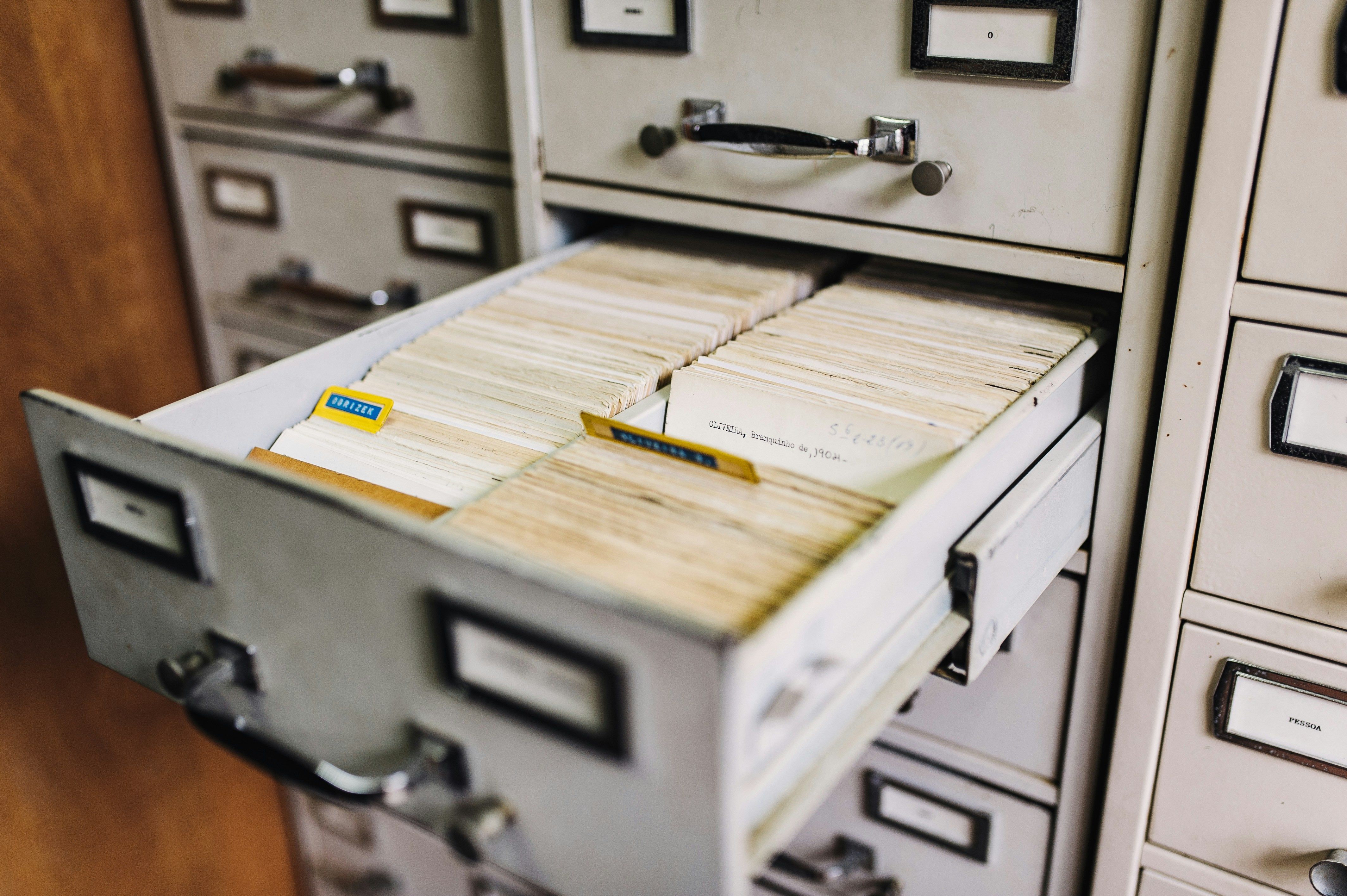 a filing cabinet filled with lots of papers and cards .