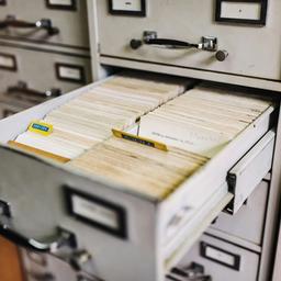 a filing cabinet filled with lots of papers and cards .