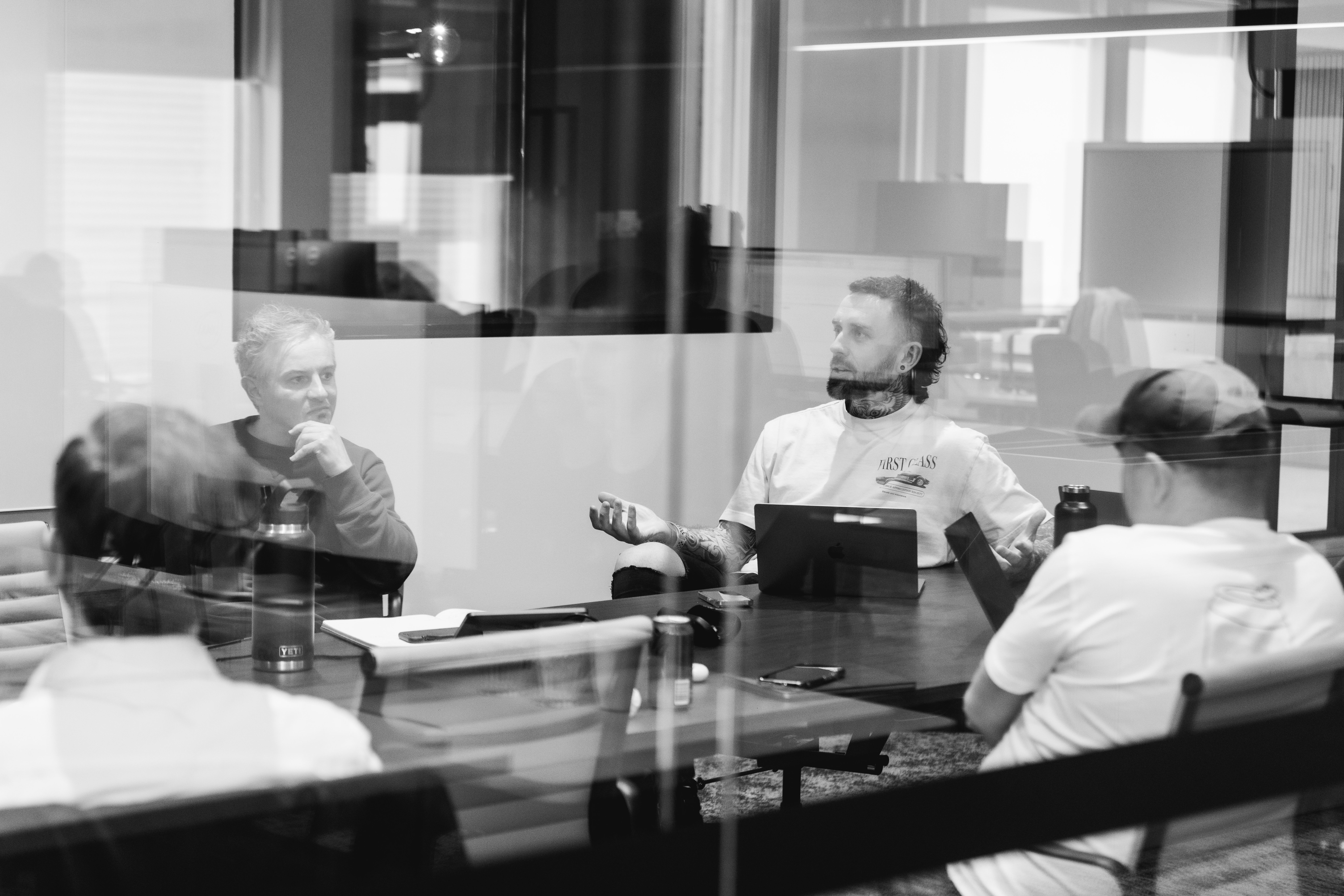 a group of men are sitting around a table in a conference room .