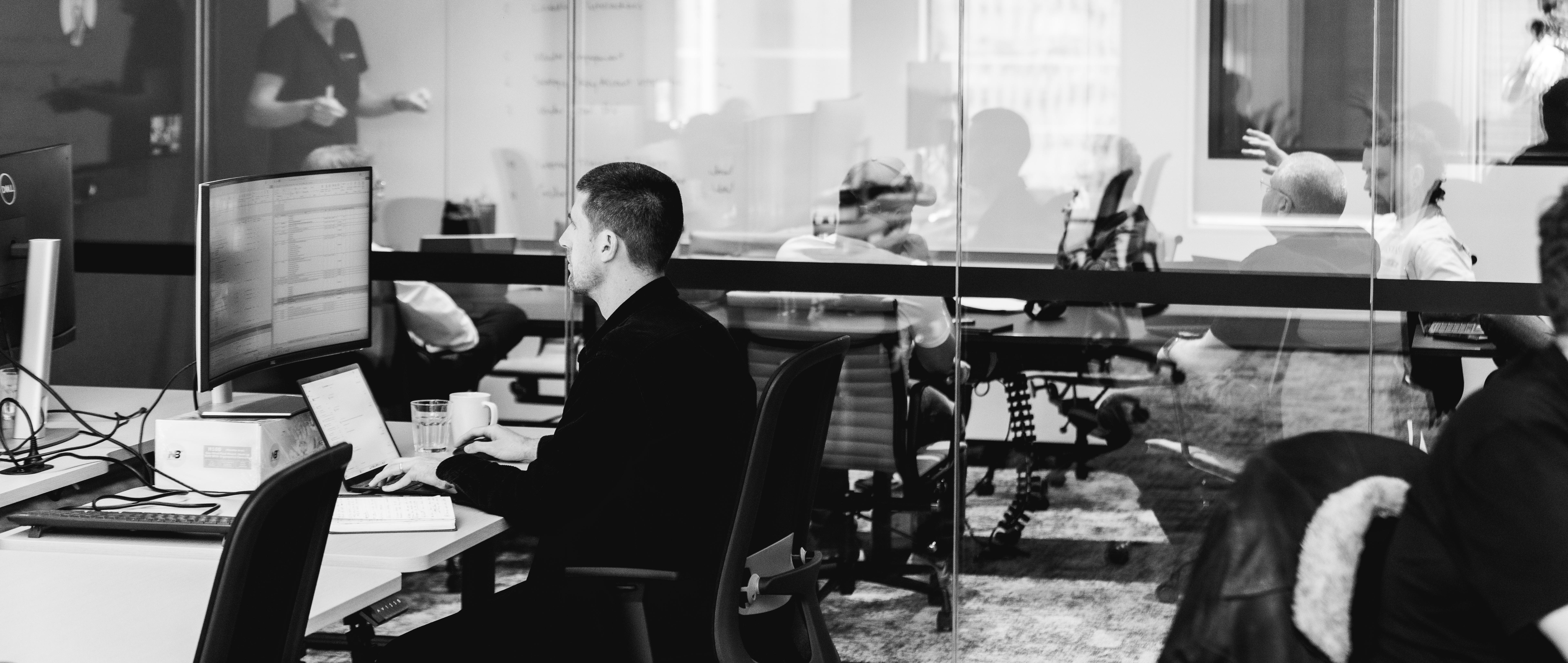 a man is sitting at a desk in front of a computer in an office .