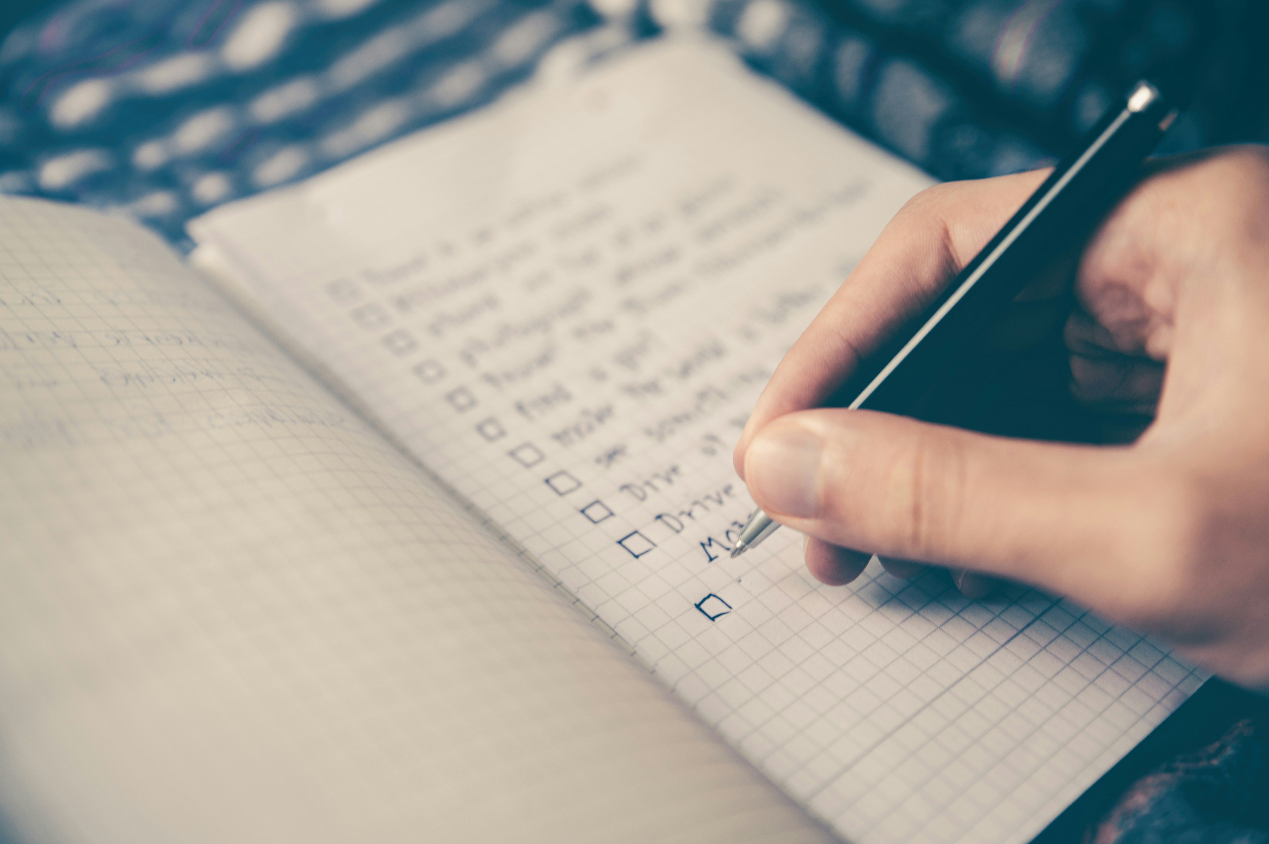 a person is writing on a checklist in a notebook with a pen .