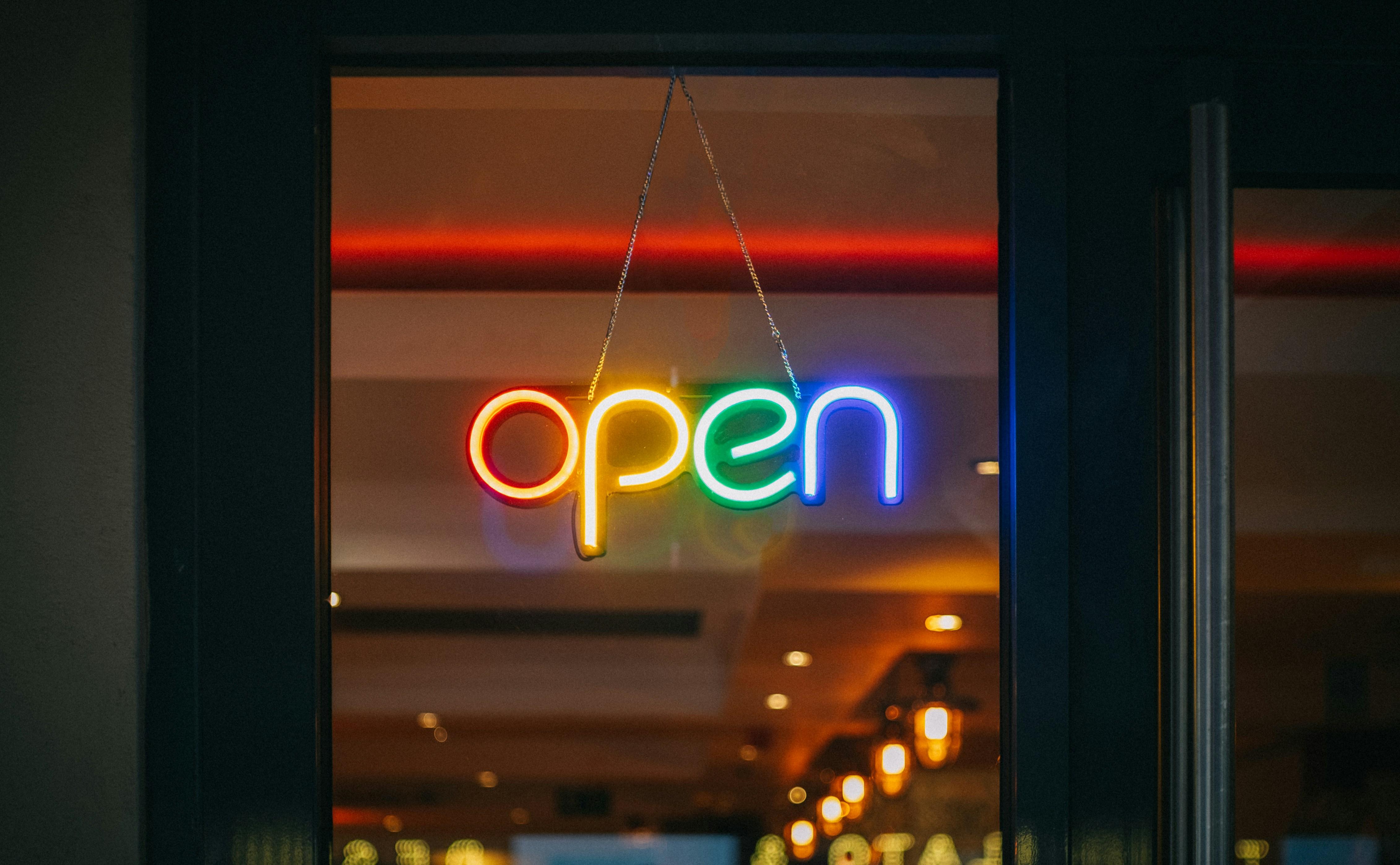 a neon sign that says `` open '' is hanging in a window .