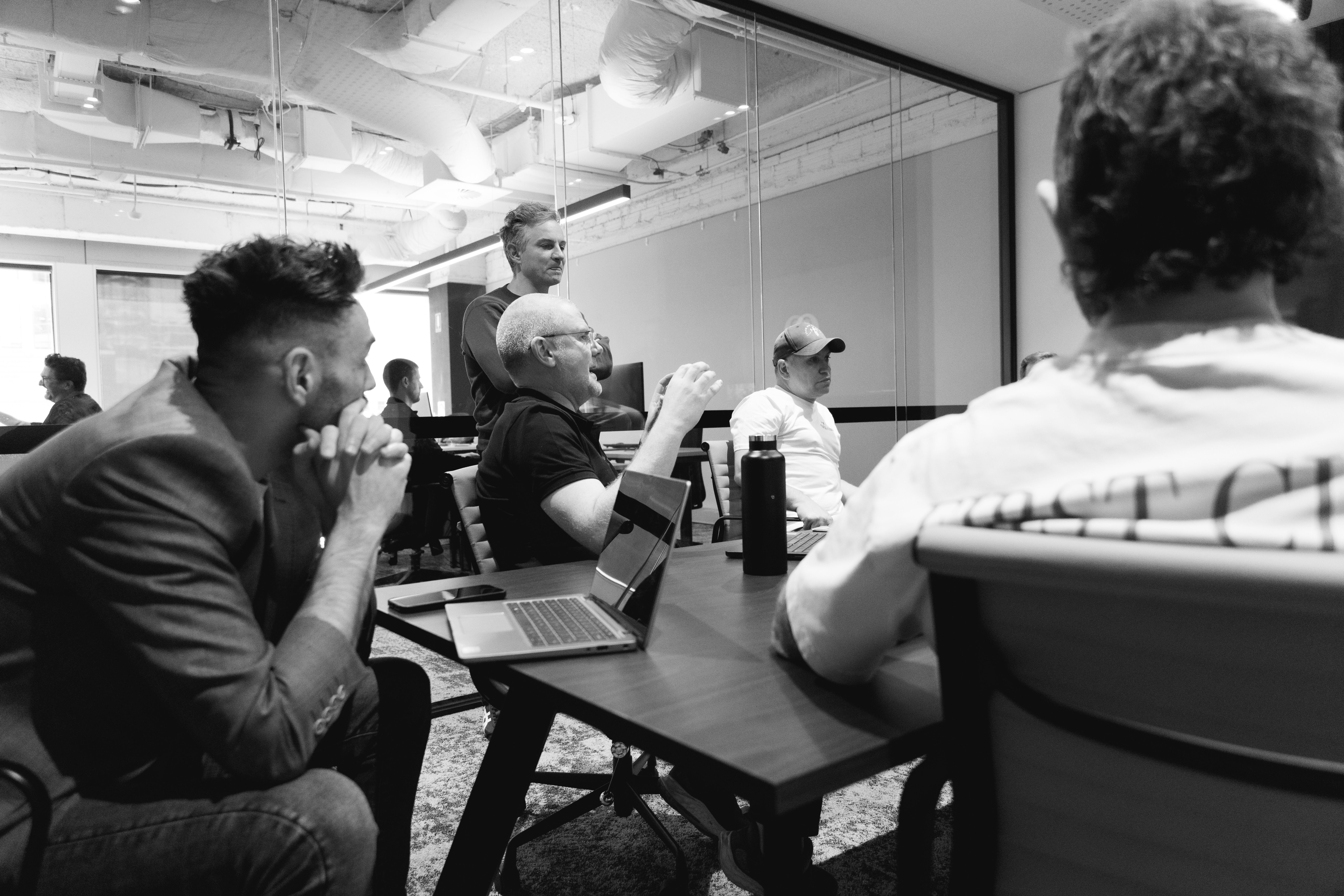 a group of men are sitting around a table in a conference room .