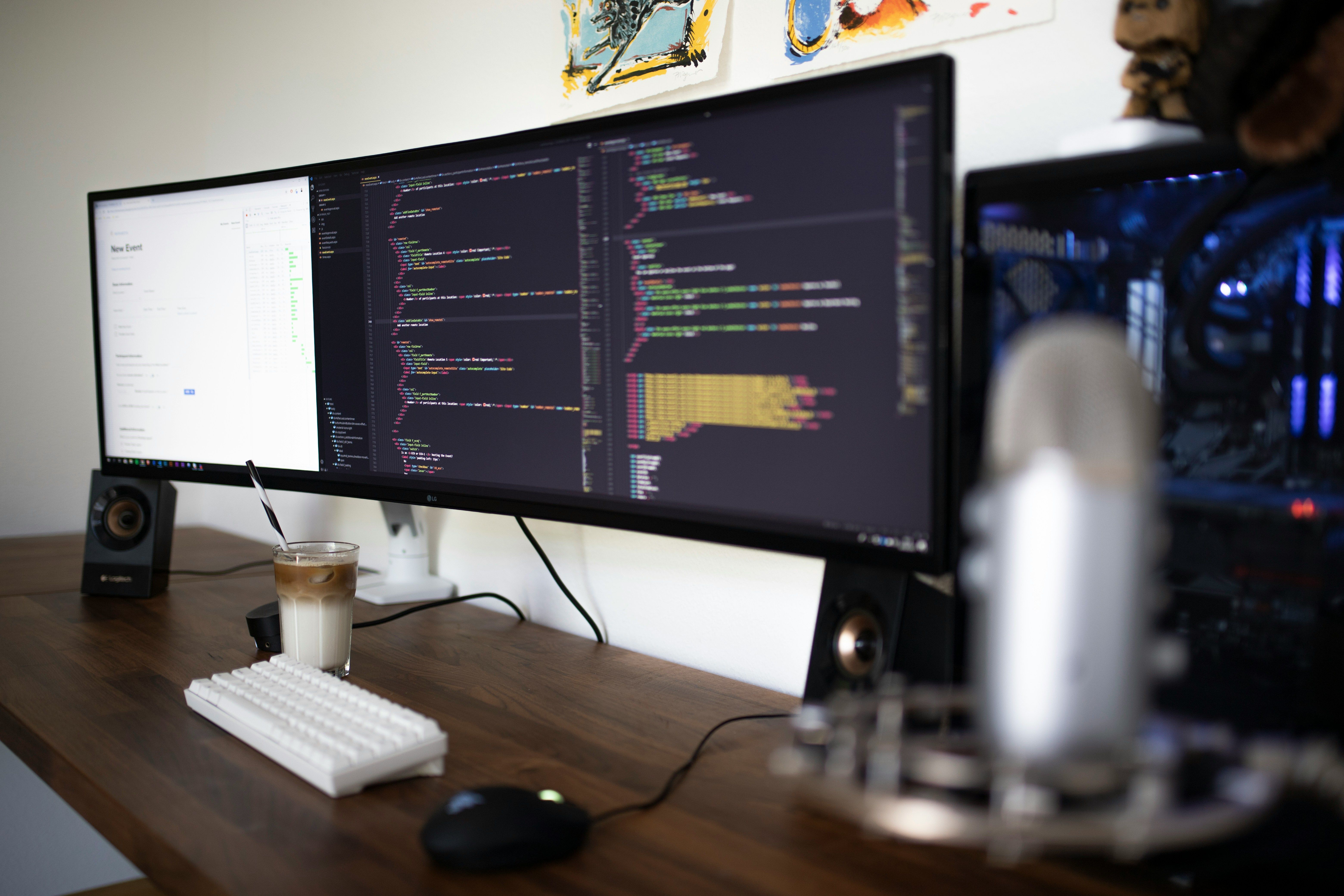a computer desk with three monitors , a keyboard , a mouse and a cup of coffee .