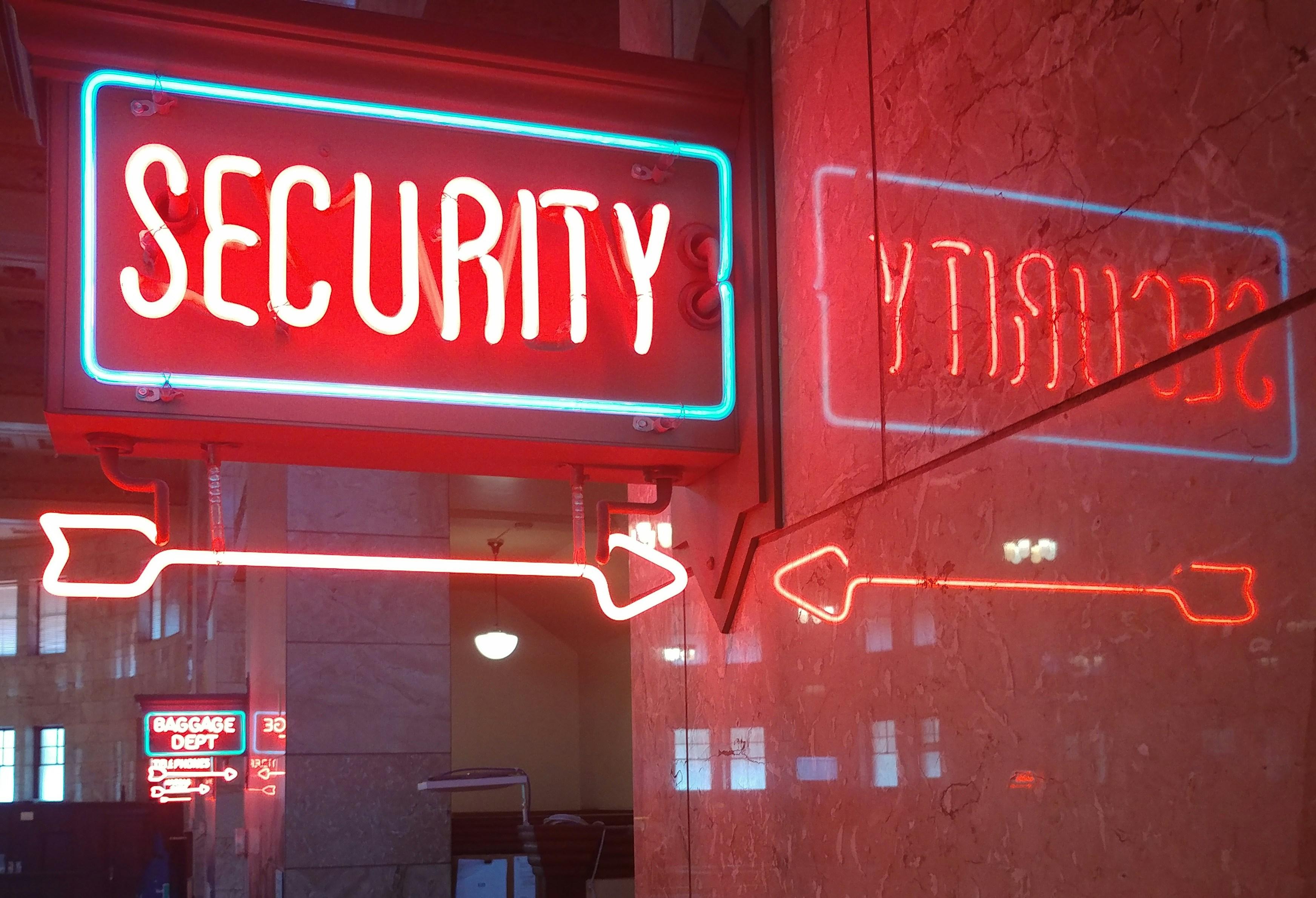 a neon sign that says `` security '' is hanging from the ceiling of a building .