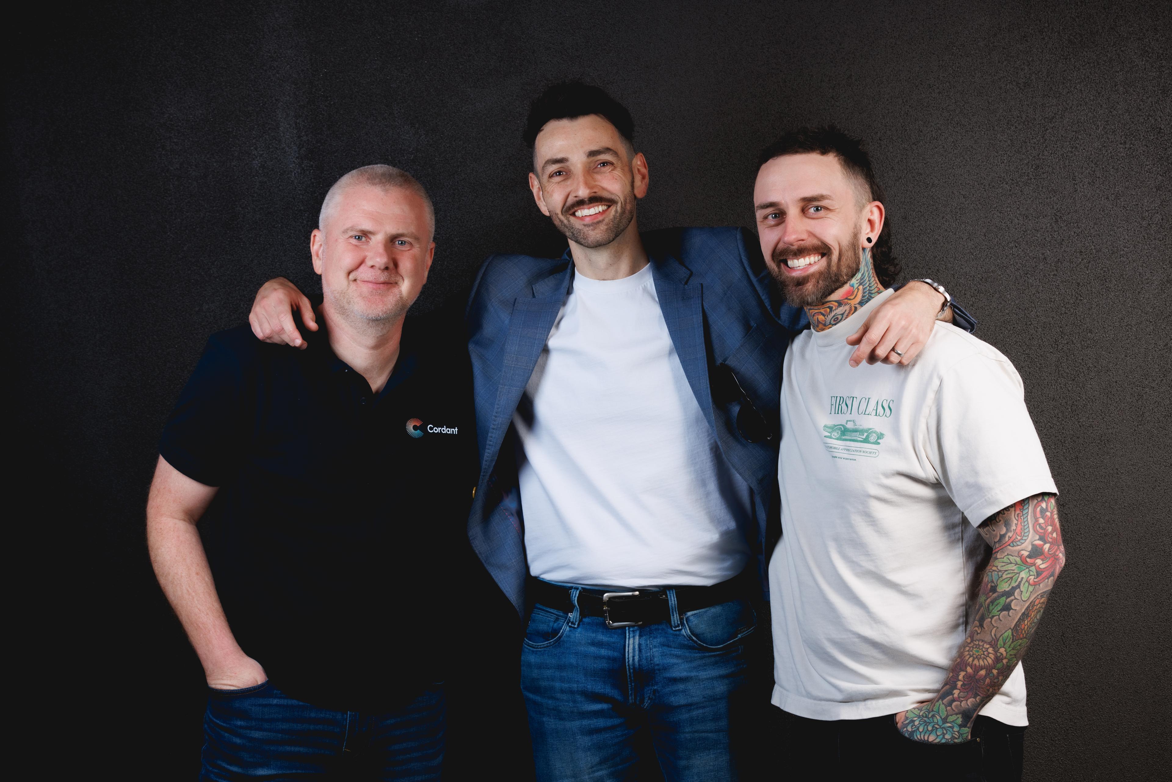 three men are posing for a picture together and smiling for the camera .
