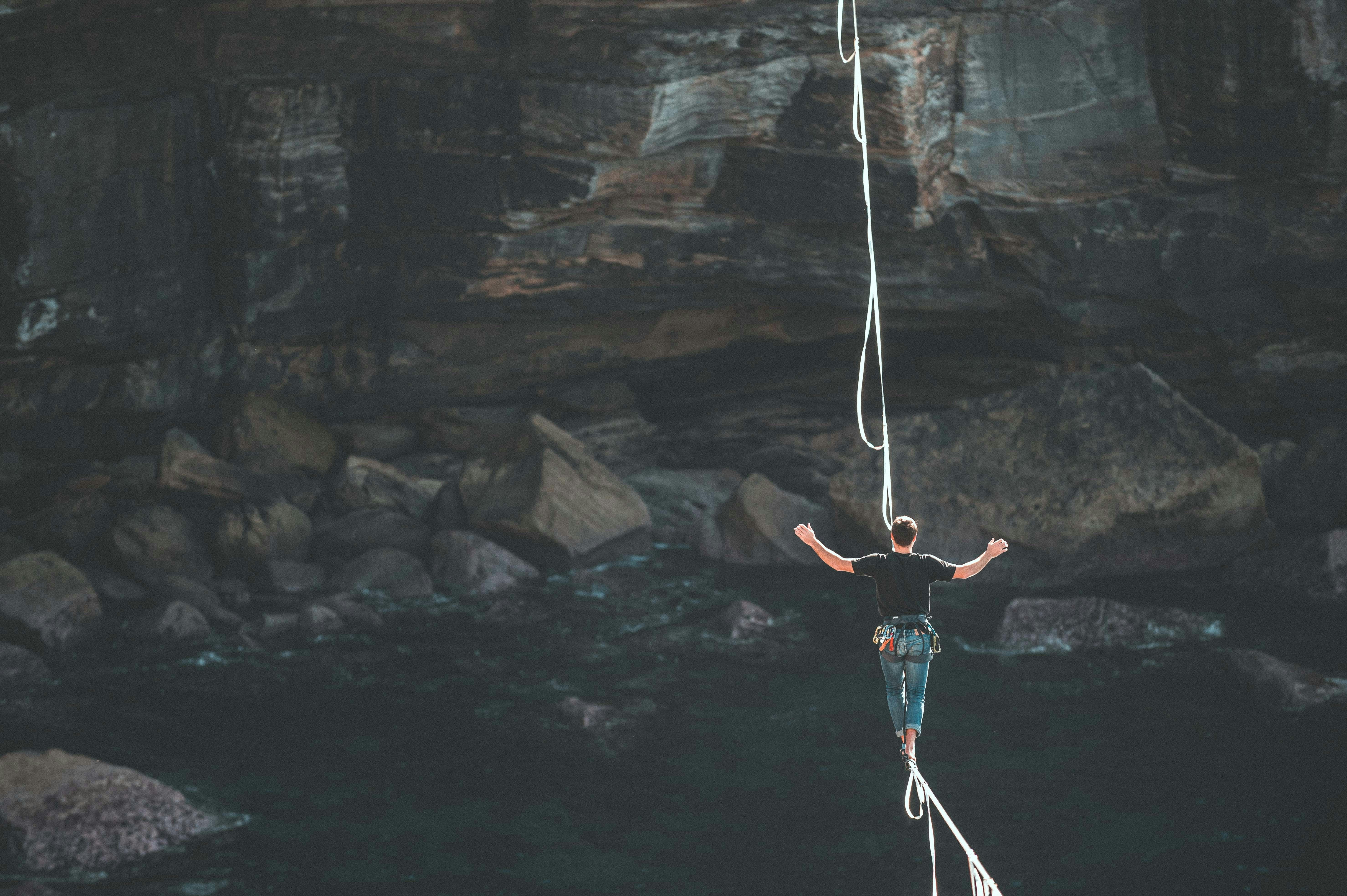 a man is walking on a rope over a body of water .