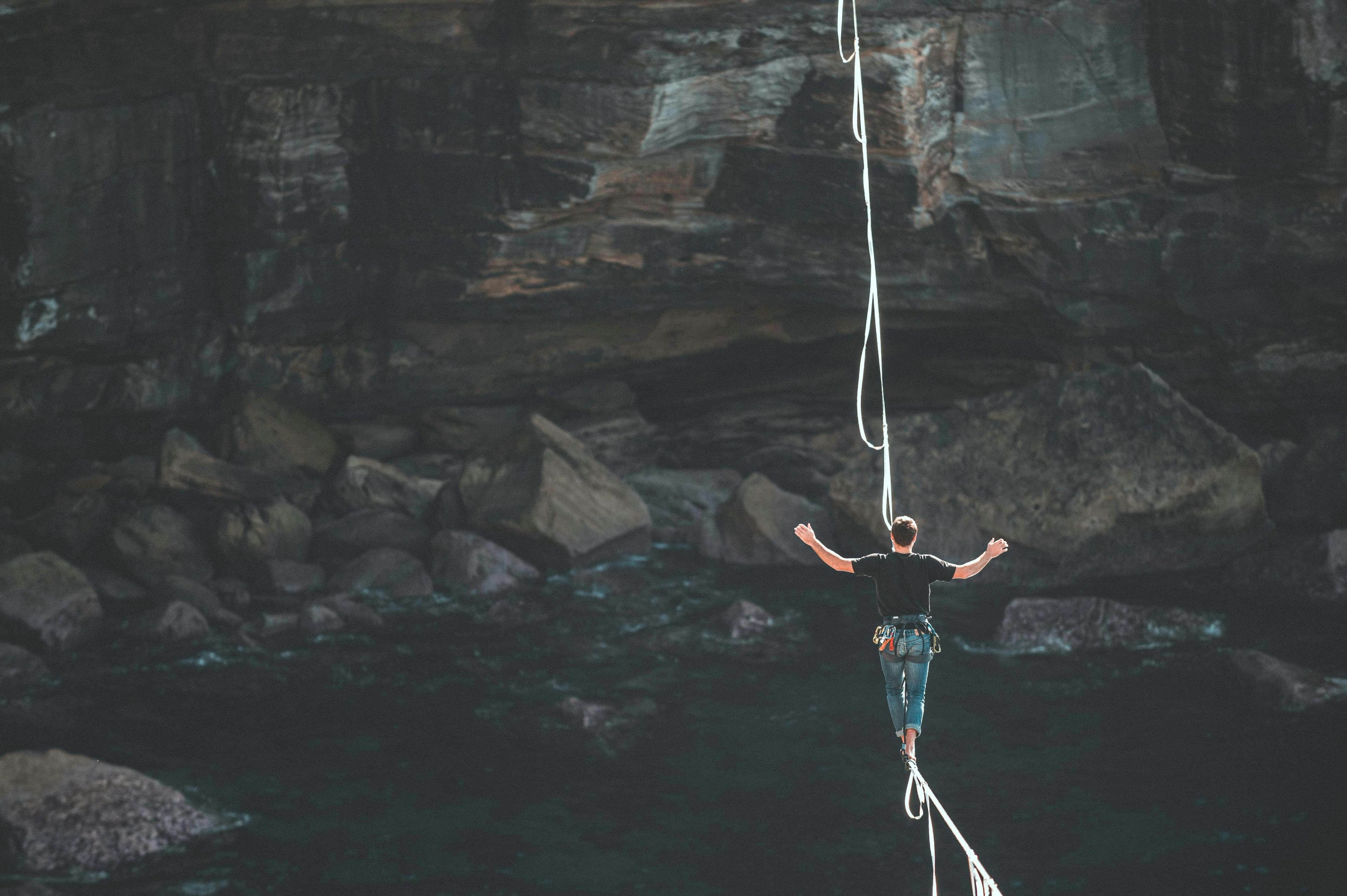 a man is walking on a rope over a body of water .