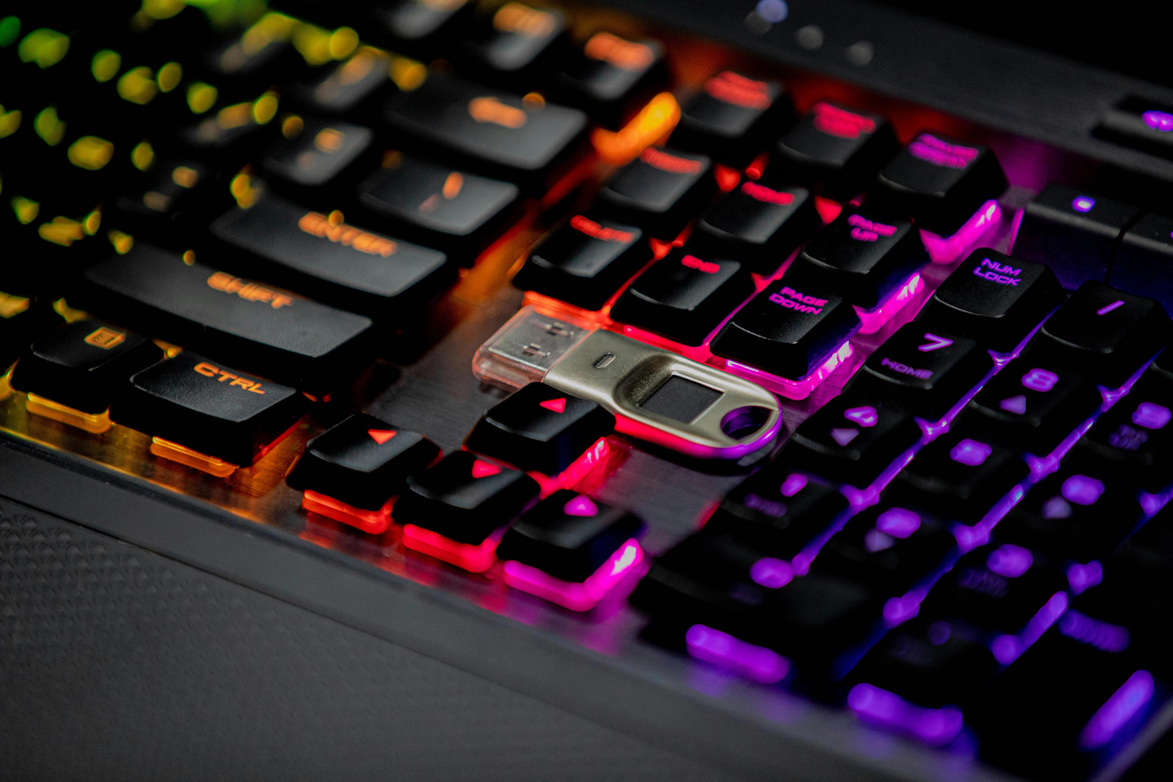 A USB flash drive rests on a colorful backlit keyboard.