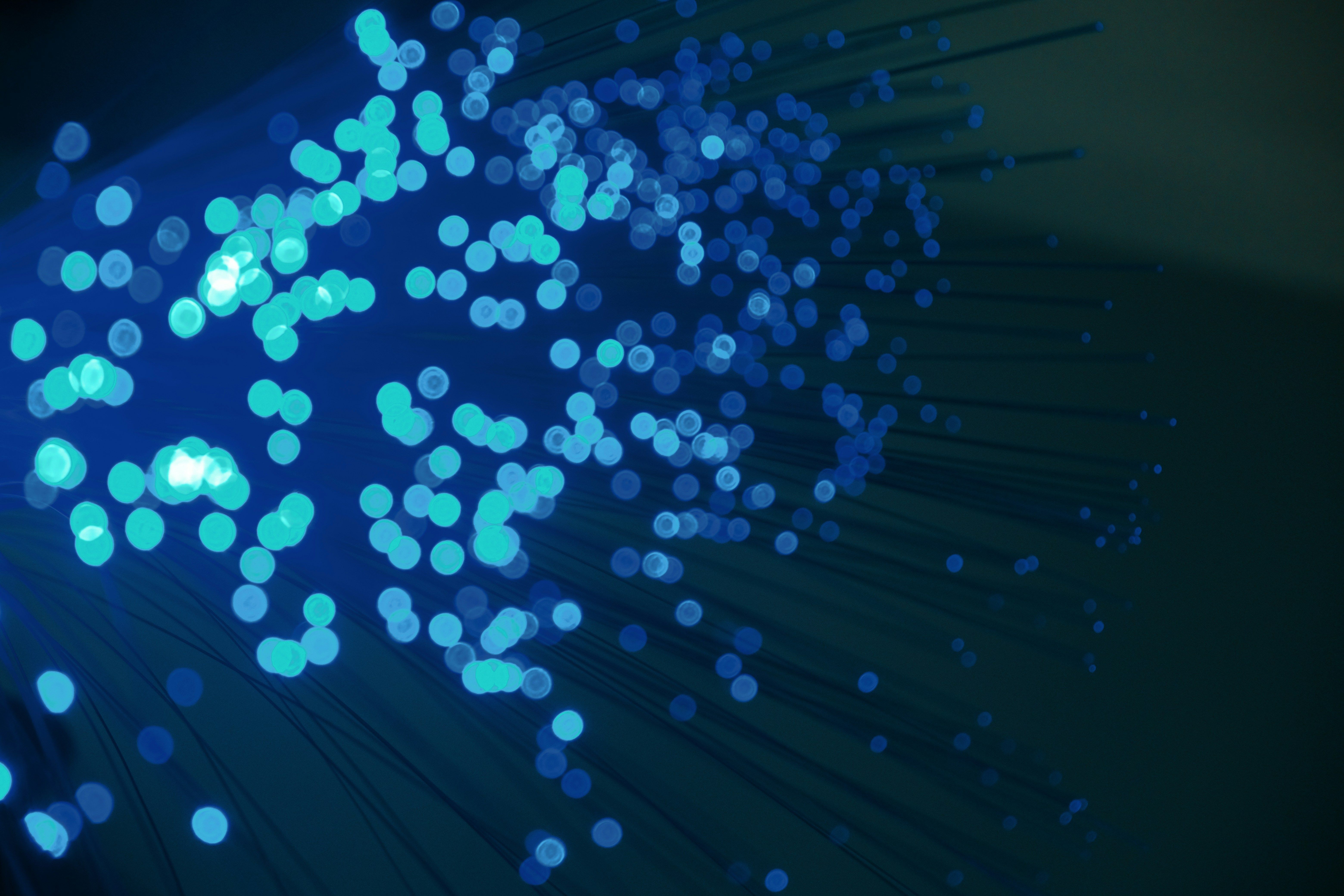 a bunch of blue dots are floating in the air on a dark background .