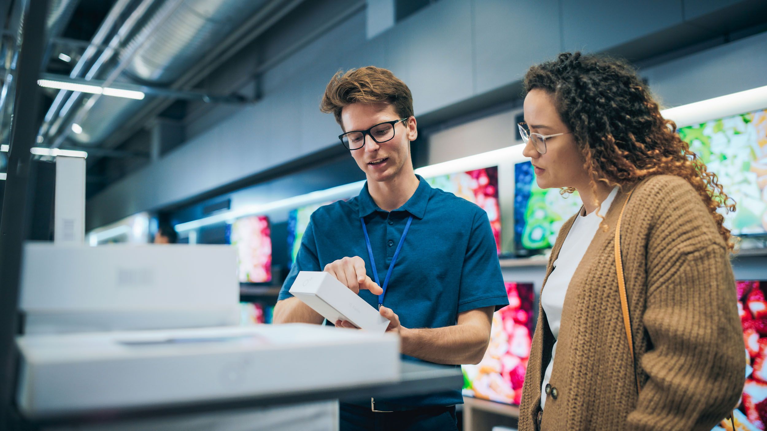 a man and a woman are looking at a box in a store .