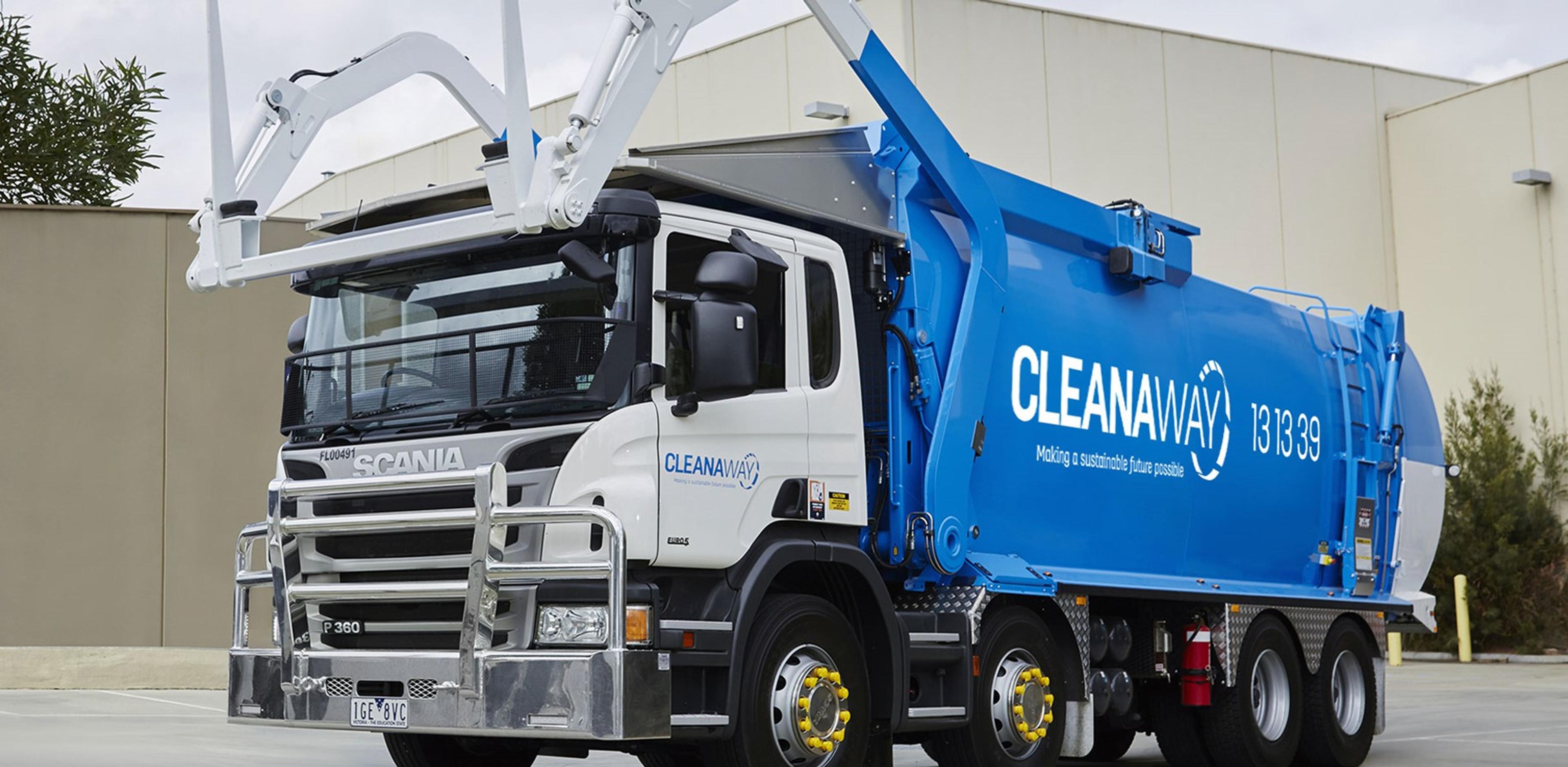 a blue and white garbage truck is parked in front of a building .