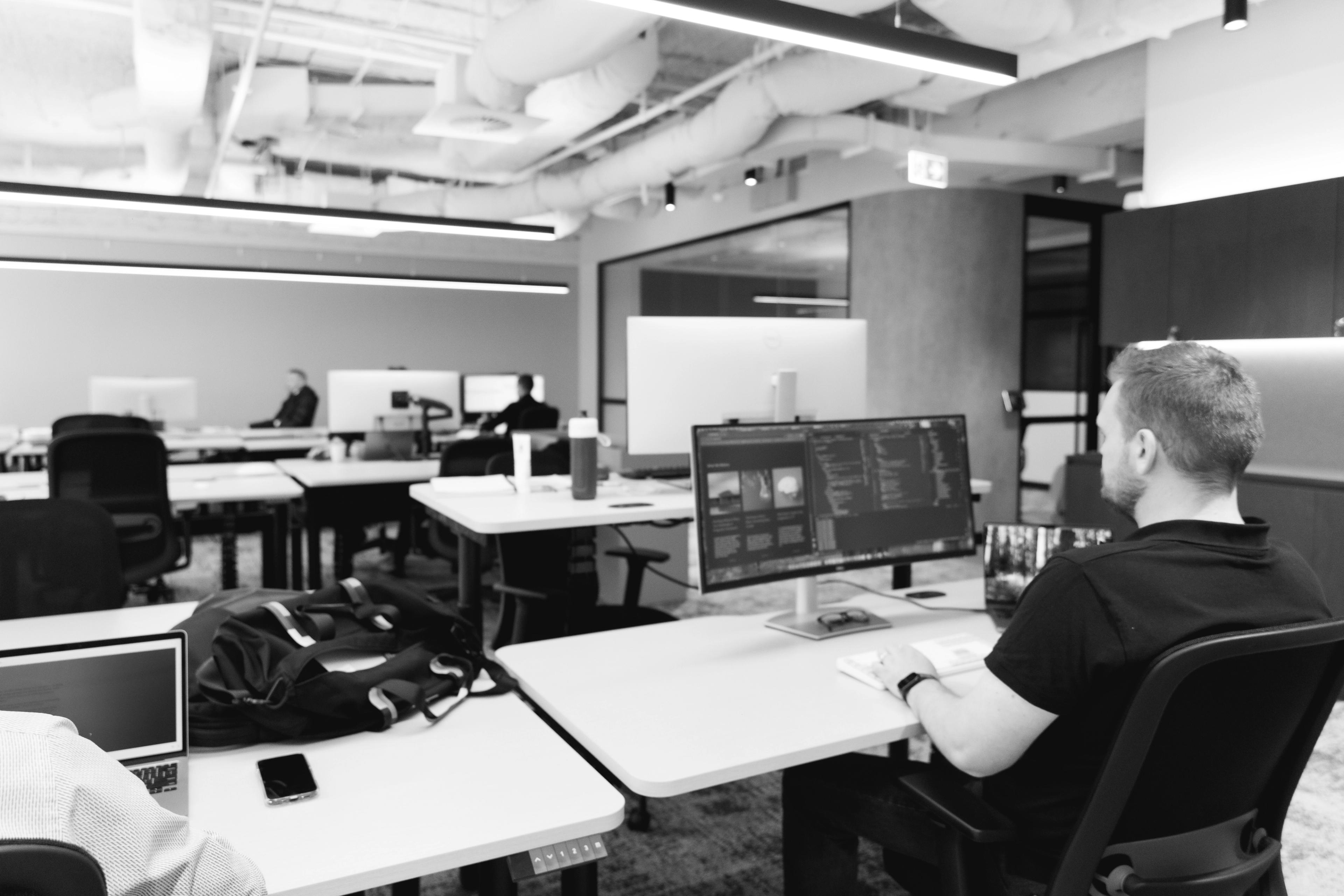 a man is sitting at a desk in an office working on a computer .