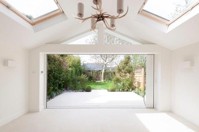 Bi-fold doors open to patio and garden with intricate lampshade and Velux windows
