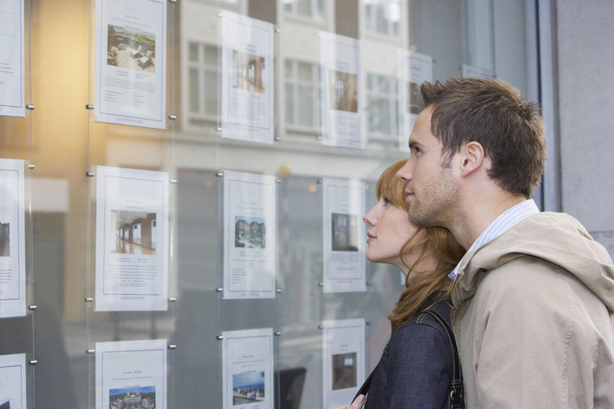 Man and women browsing property adverts in estate agent window