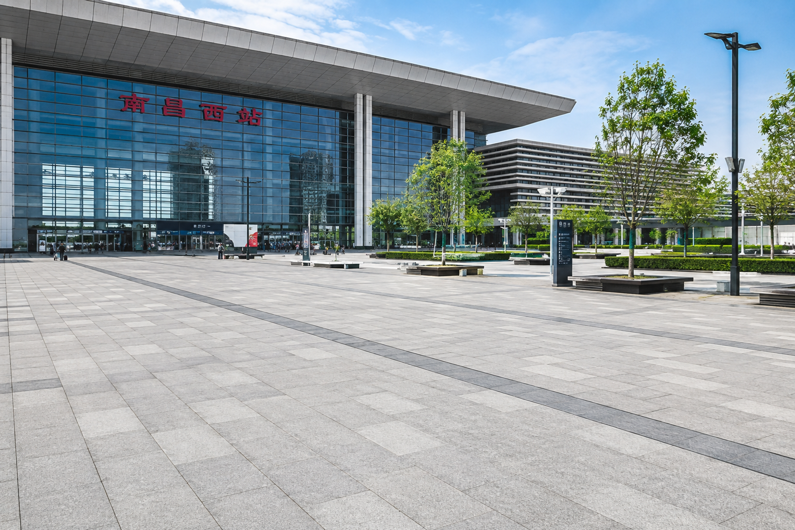 Large-format custom natural granite slabs paving a transport hub forecourt, creating a spacious pedestrian area that connects naturally with the modern building entrance