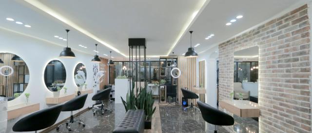 Il salone con le poltrone nere, gli specchi rotondi e il muro di mattoni