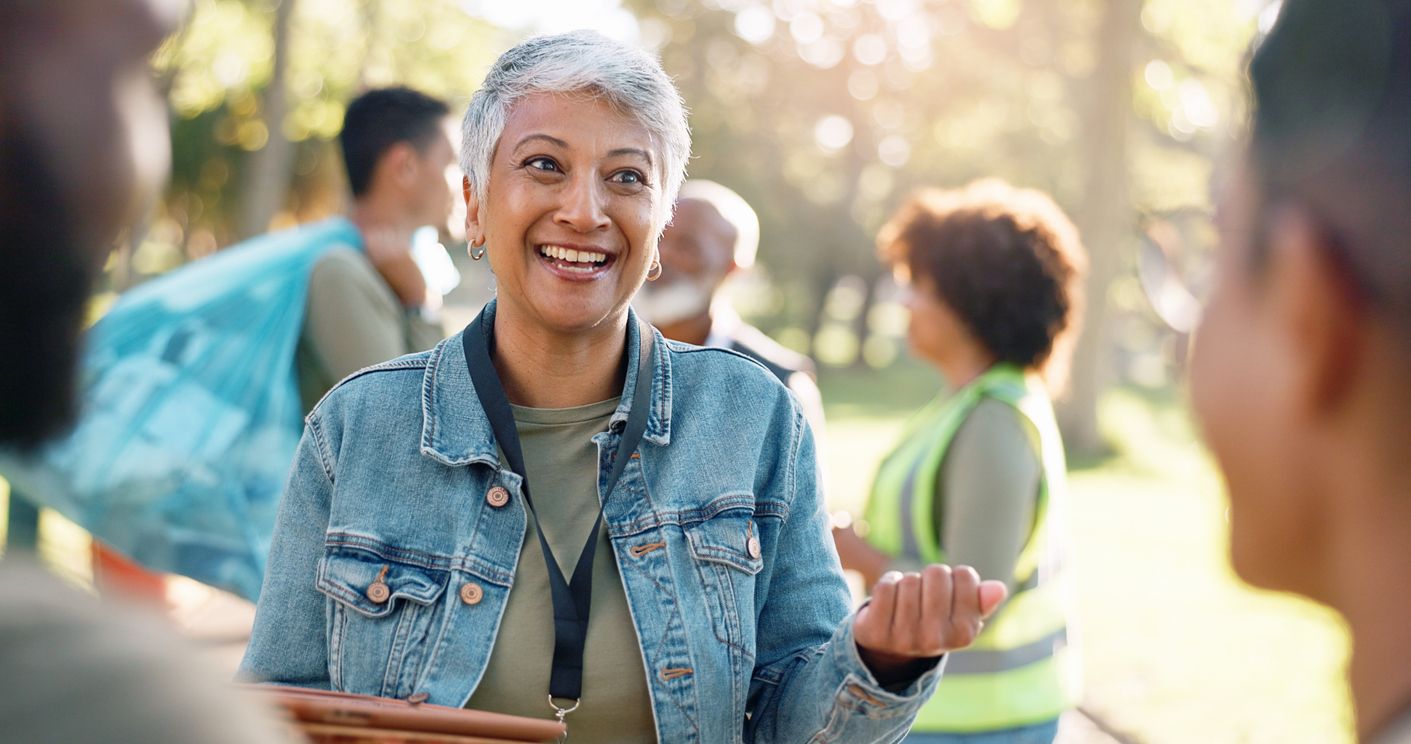 Older woman volunteering in a park with peers in the background