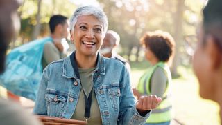 Older woman volunteering in a park with peers in the background