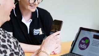 An Assistive Technology specialist works with a Client using their smartphone and a laptop.