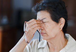 Person pinching nose in discomfort after removing glasses