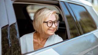 Smiling older person looking out car window from passenger seat