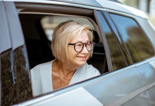 Smiling older person looking out car window from passenger seat