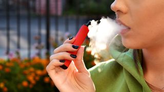 Person vaping with a close up on their hand and mouth
