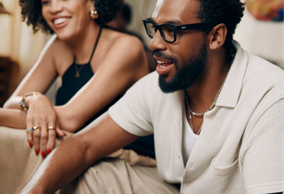 Man wearing meta smart glasses talking with a friend on a couch