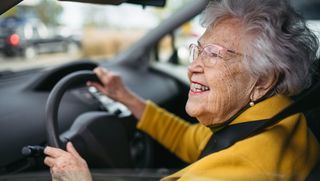 Happy older woman driving car