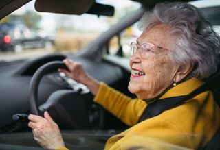 Happy older woman driving car