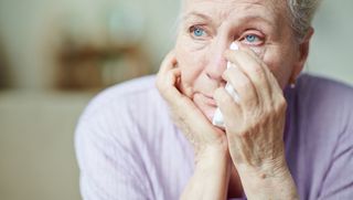 Older person wiping eyes with tissue