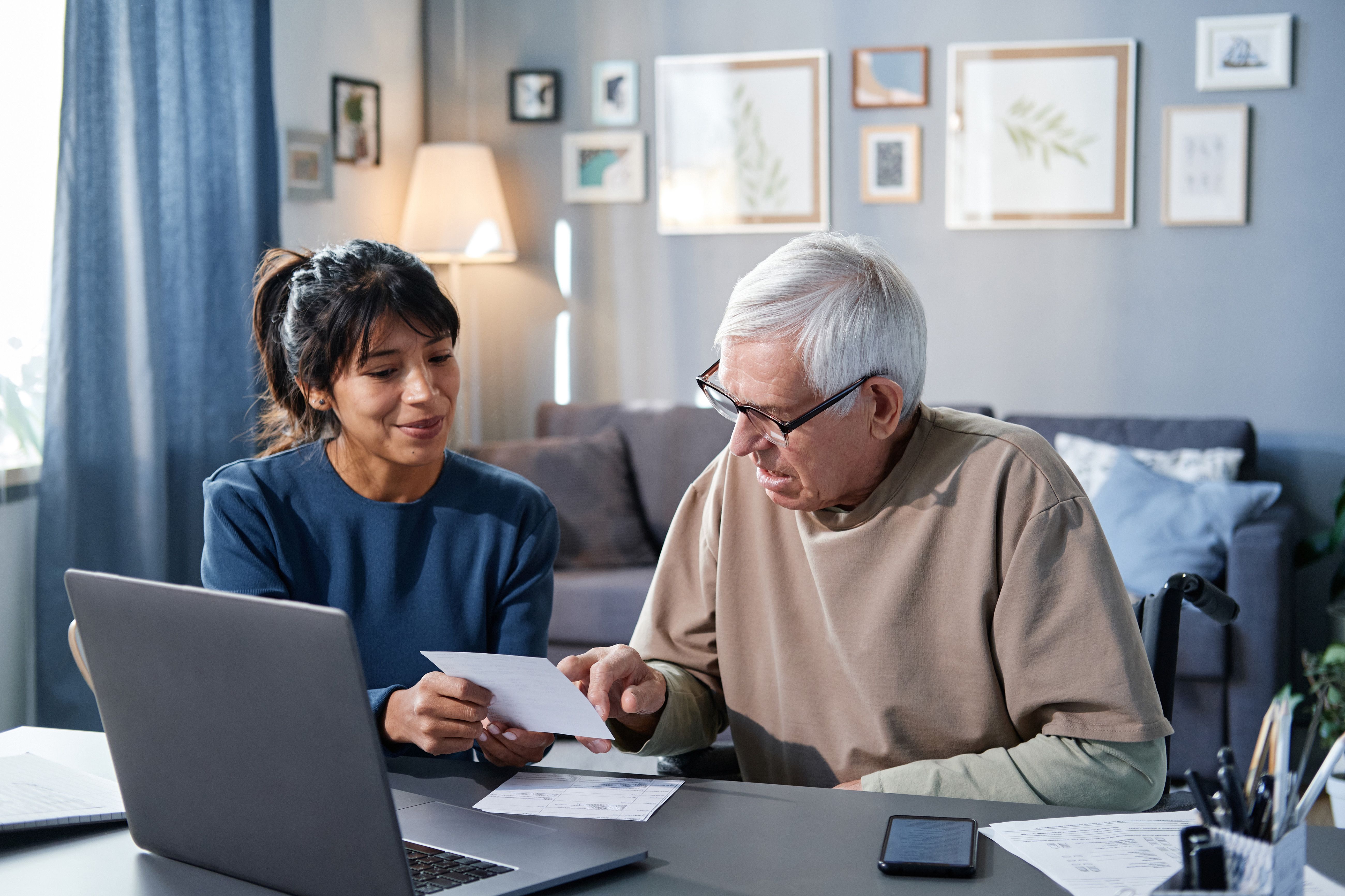 Orthoptist sitting in a home office with a Client while they read a piece of paper.