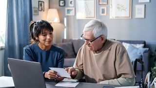 Orthoptist sitting in a home office with a Client while they read a piece of paper.