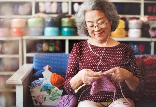 Older person knitting while listening to music using headphones