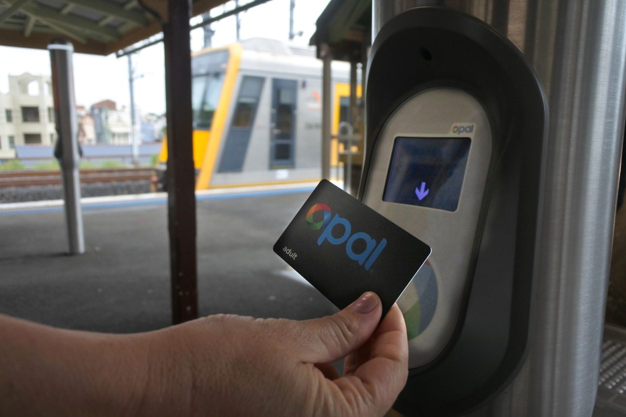 Close up of hand using Opal card at train platform
