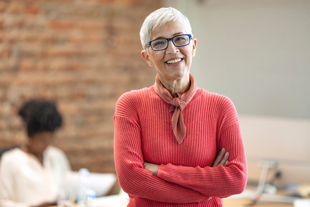 Older woman smiling with her arms crossed in an office