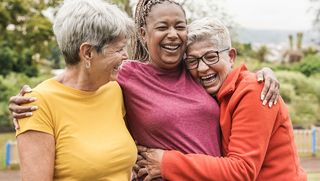 Group of three older people hugging outdoors