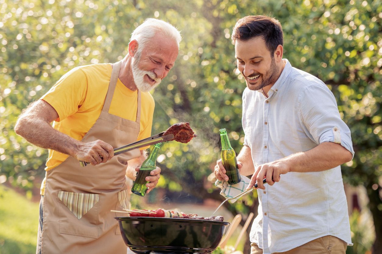 Older man barbecuing with younger peer