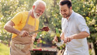 Older man barbecuing with younger peer