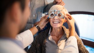 An older woman smiling while have her eyes tested.