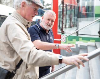 An Orientation and Mobility specialist working with a Client to navigate a set of stairs outside.