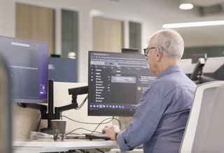 A man works at his desk using two monitors with magnified screens.