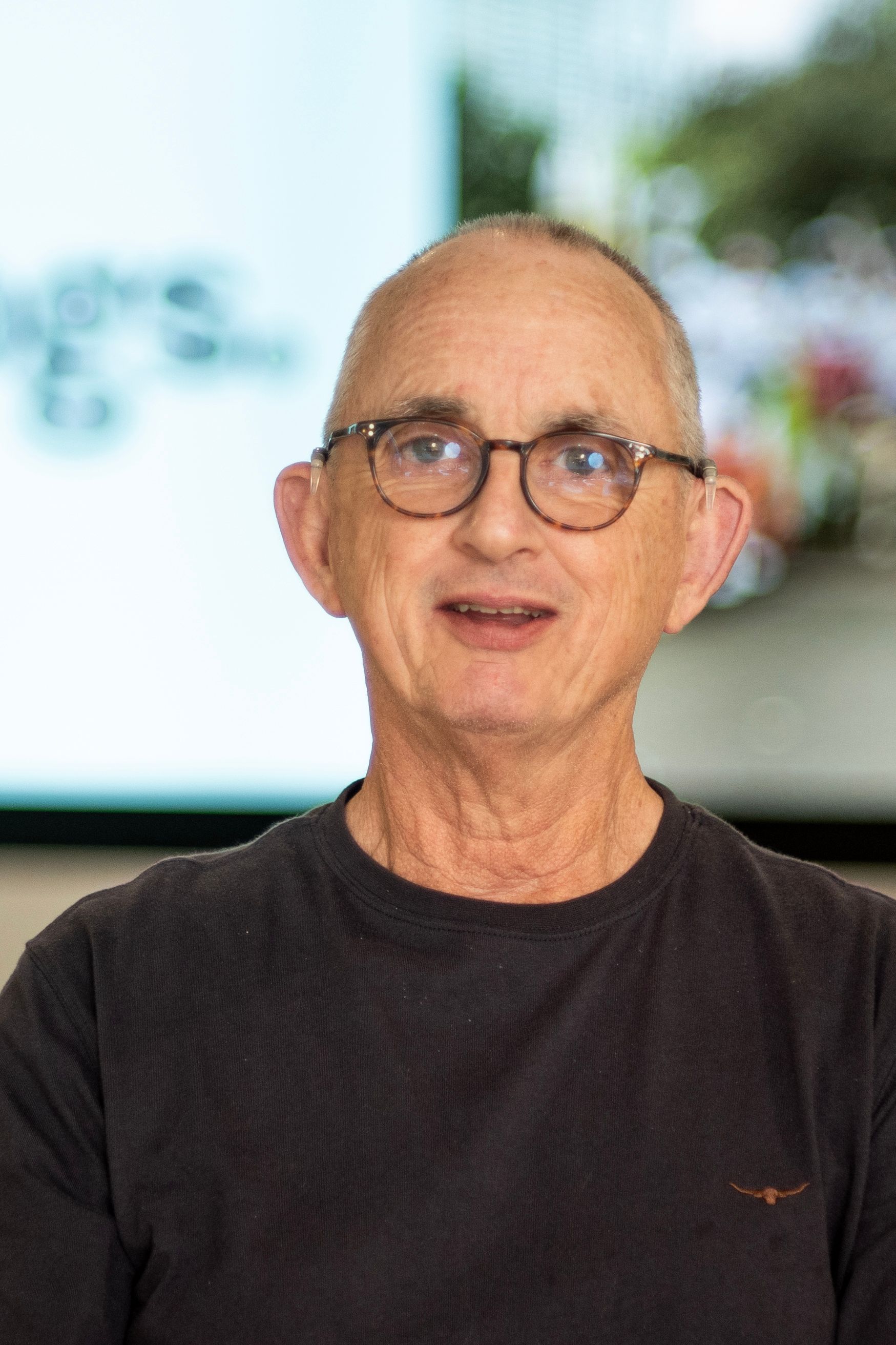 A photo of Alan wearing glasses and a black shirt