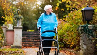 Older person walking in park using a mobility walker