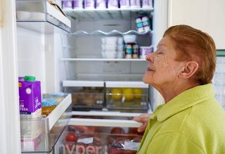 Older person looking at items in fridge